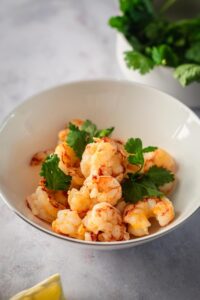 A white bowl that is filled with shrimp.