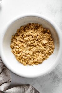 White bowl filled with combined almond flour pie crust ingredients.