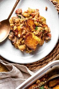 Part of a white plate with stuffing on it and part of a spoon next to it.