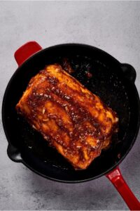 A skillet with a marinated pork loin roast in it.