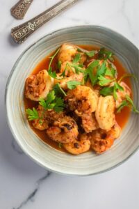 A bunch of shrimp in a gray bowl on a white counter.