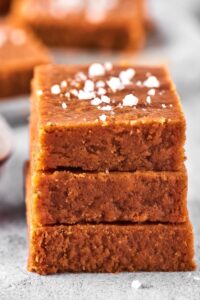 Three pieces of peanut butter fudge evenly stacked on top of one another on a gray counter.