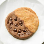 A cookie that's half chocolate and half peanut butter on a white plate.