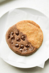 A cookie that's half chocolate and half peanut butter on a white plate.