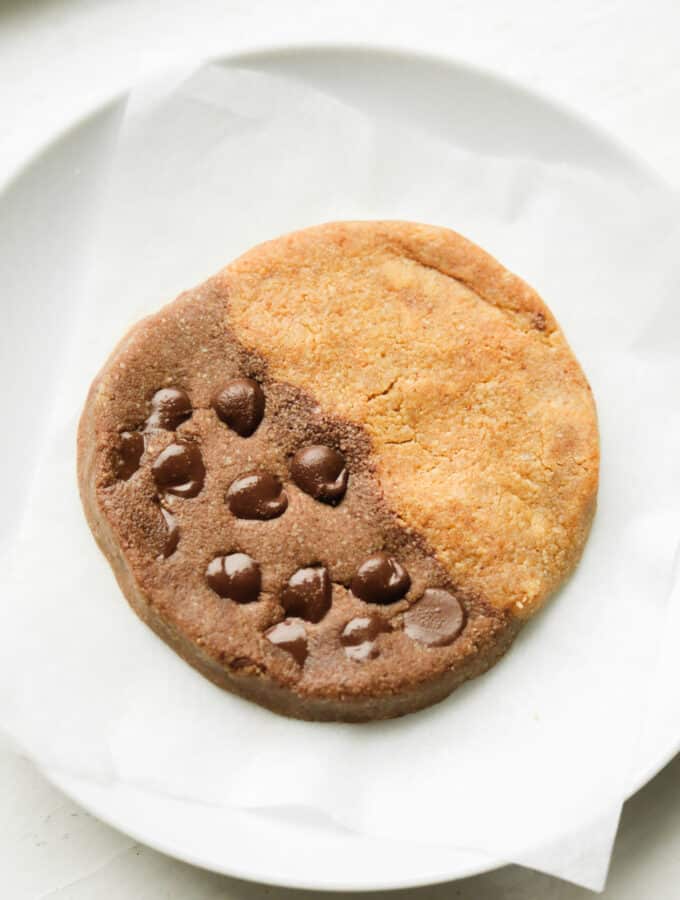 A cookie that's half chocolate and half peanut butter on a white plate.