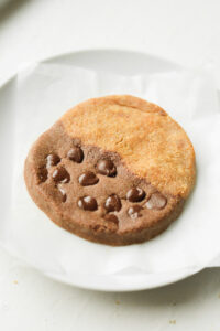 A cookie set on a white plate lined with a sheet of parchment paper.