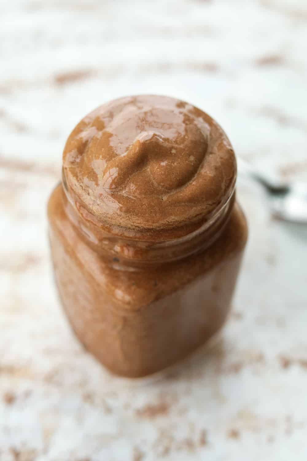 A chocolate frosty inside of a clear jar. The jar is set on a white table.