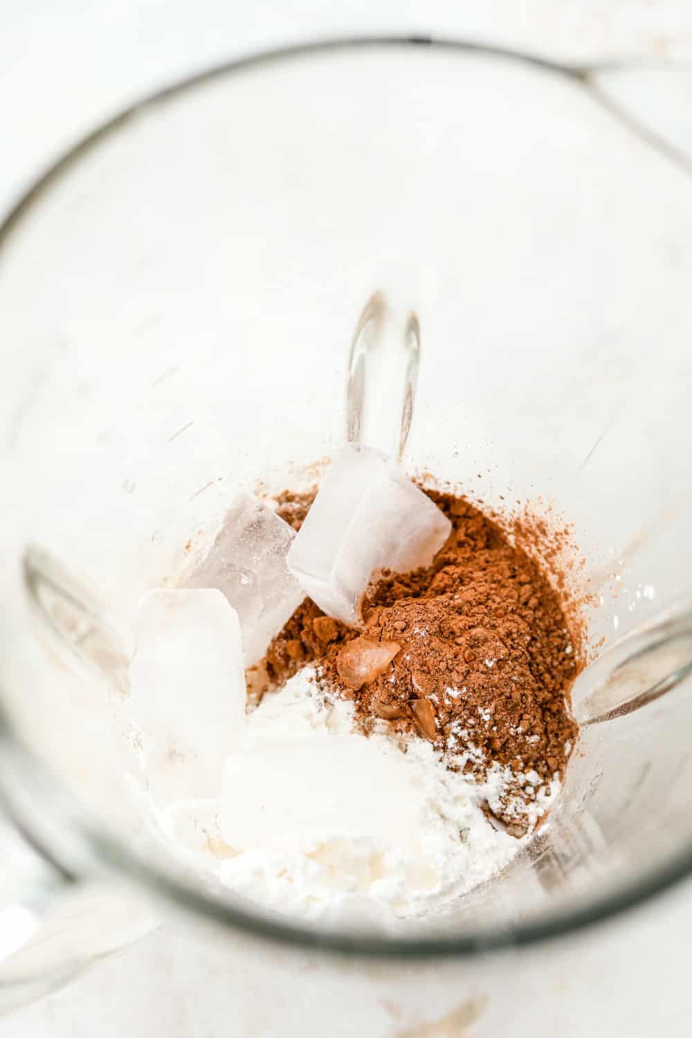 Cocoa powder, protein powder, sweetener, and ice in a blender.