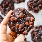 A hand holding a chocolate nut cluster.