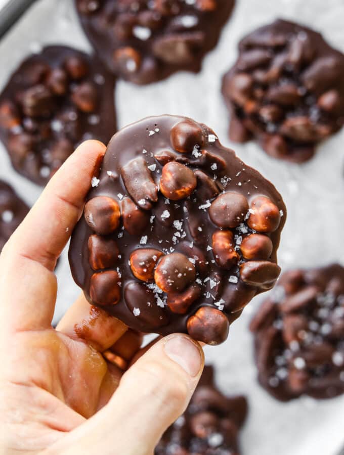 A hand holding a chocolate nut cluster.