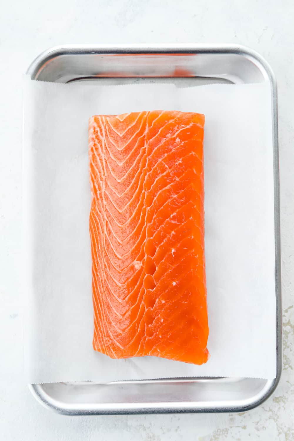 A raw salmon filet in a tin tray.
