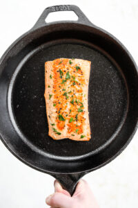 A cooked salmon filet in a black cast iron pan.