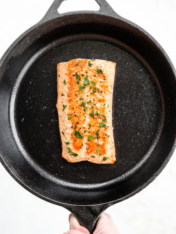 A cooked salmon filet in a black cast iron pan.