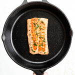 A cooked salmon filet in a cast iron pan.