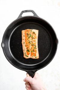 A cooked salmon filet in a cast iron pan.