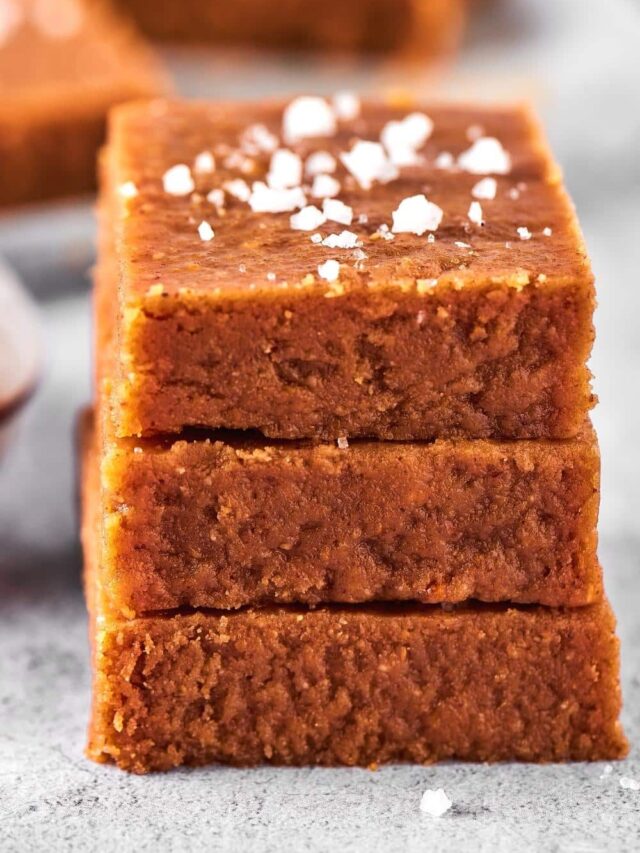 Three pieces of peanut butter fudge evenly stacked on top of one another on a gray counter.
