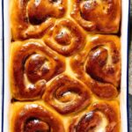 A baking dish with eight cinnamon Rolls in it.
