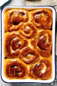 A baking dish with eight cinnamon Rolls in it.