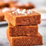 Three squares of peanut butter fudge stacked on top of one another on a gray counter.