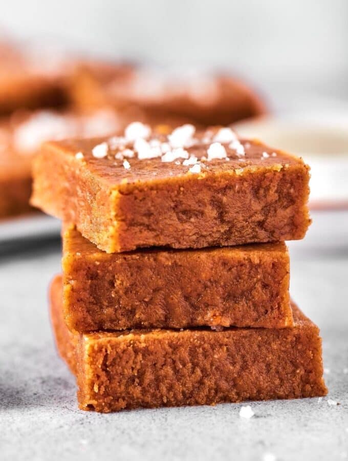 Three squares of peanut butter fudge stacked on top of one another on a gray counter.