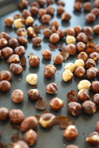 A baking pan with roasted hazelnuts on it.