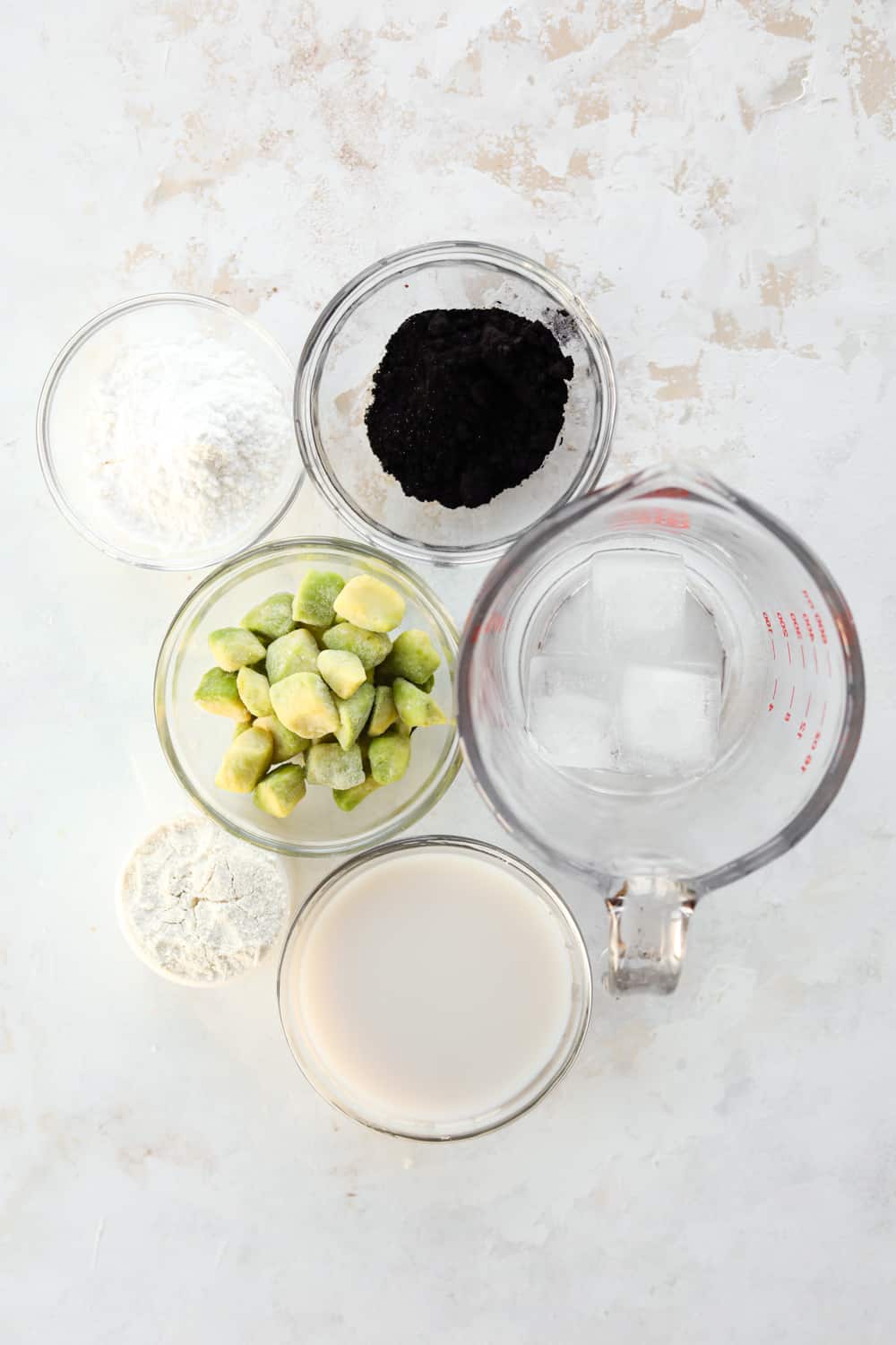 A variety of glass ramekins filled with ingredients on a white table.