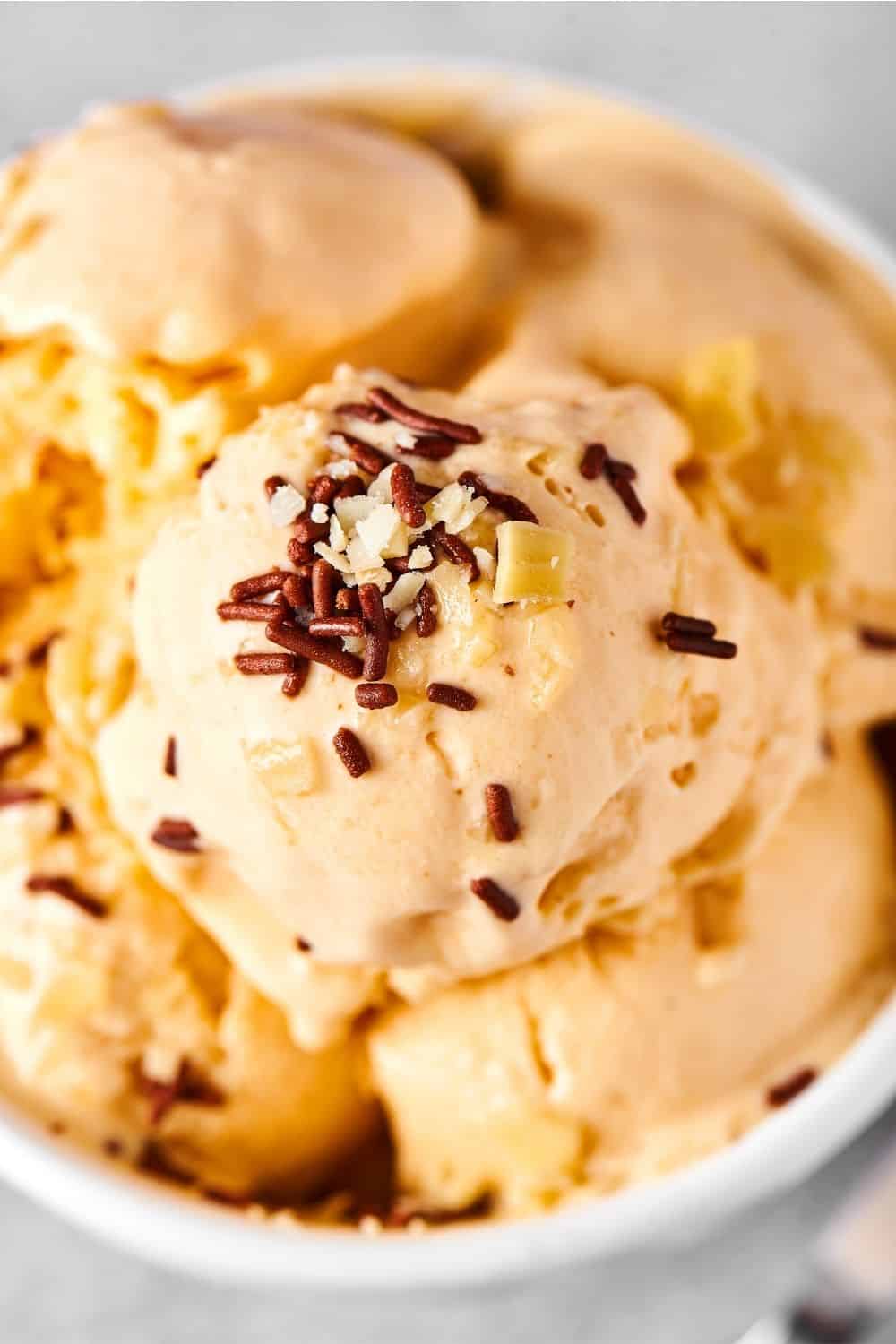 A scoop of almond milk ice cream on top of more ice cream in a white bowl.