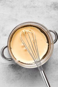 And almond milk ice cream mixture in a pot with a whisk in top of the mixture.