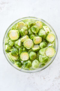 A bowl of cut up brussels sprouts soaked in water.