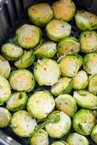 Uncooked halved brussels sprouts in an air fryer.