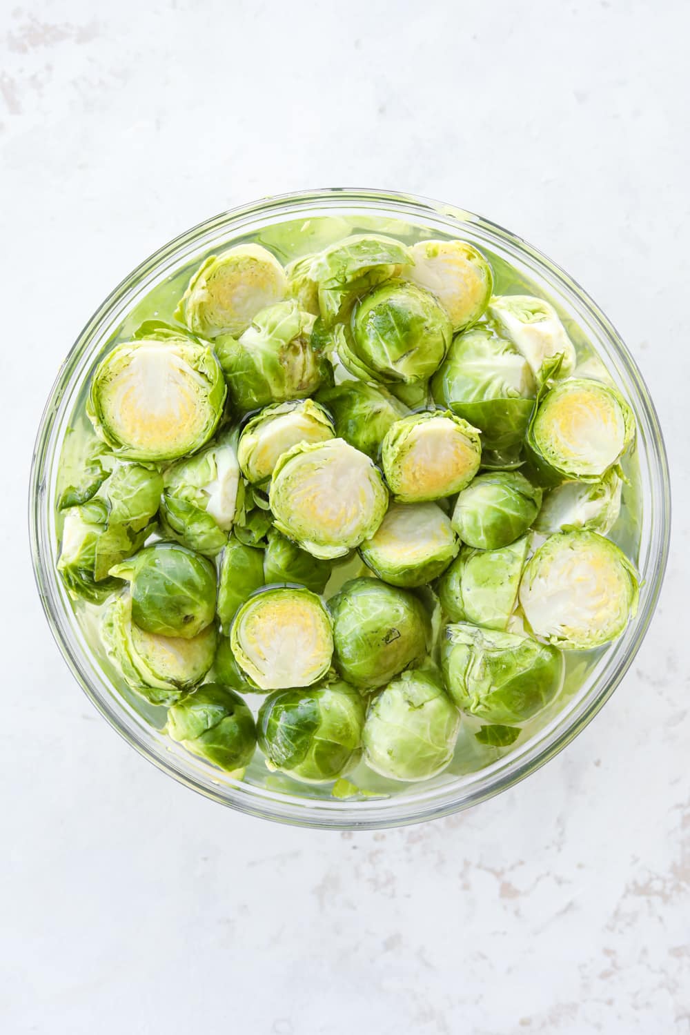 A bowl of cut up brussels sprouts soaked in water.