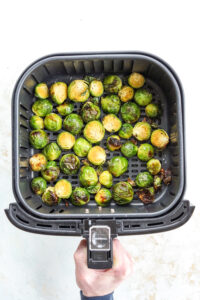 An air fryer full of roasted brussels sprouts.