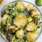 A bowl of roasted brussels sprouts topped with Parmesan cheese and flaky salt.