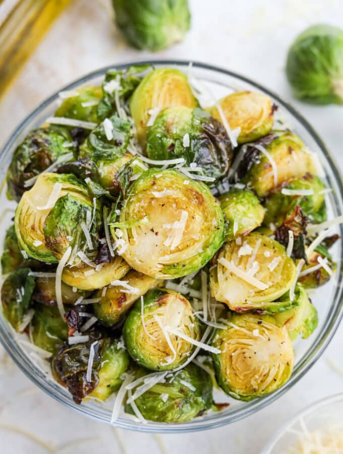 A bowl of roasted brussels sprouts topped with Parmesan cheese and flaky salt.