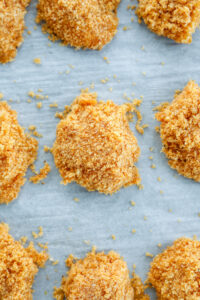 Uncooked chicken nuggets on a white sheet of parchment paper.