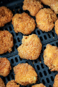 Cooked chicken nuggets in an air fryer basket.