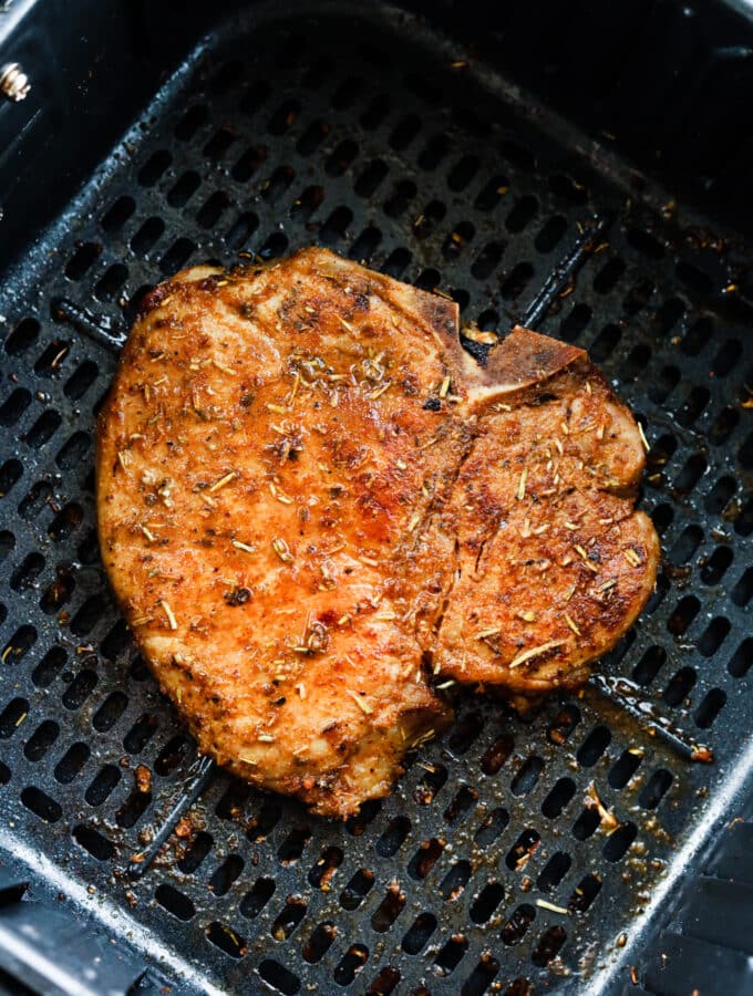 A cooked pork chop in an air fryer basket.