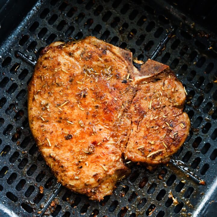 A cooked pork chop in an air fryer basket.