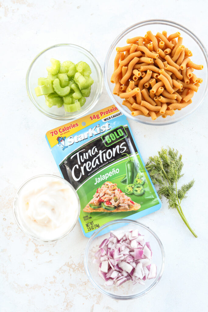 Ingredients to make tuna salad on a white table.