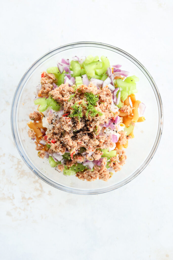 Clear glass bowl filled with unmixed tuna salad.