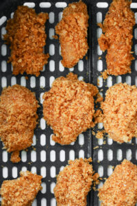 Uncooked chicken nuggets in an air fryer basket.