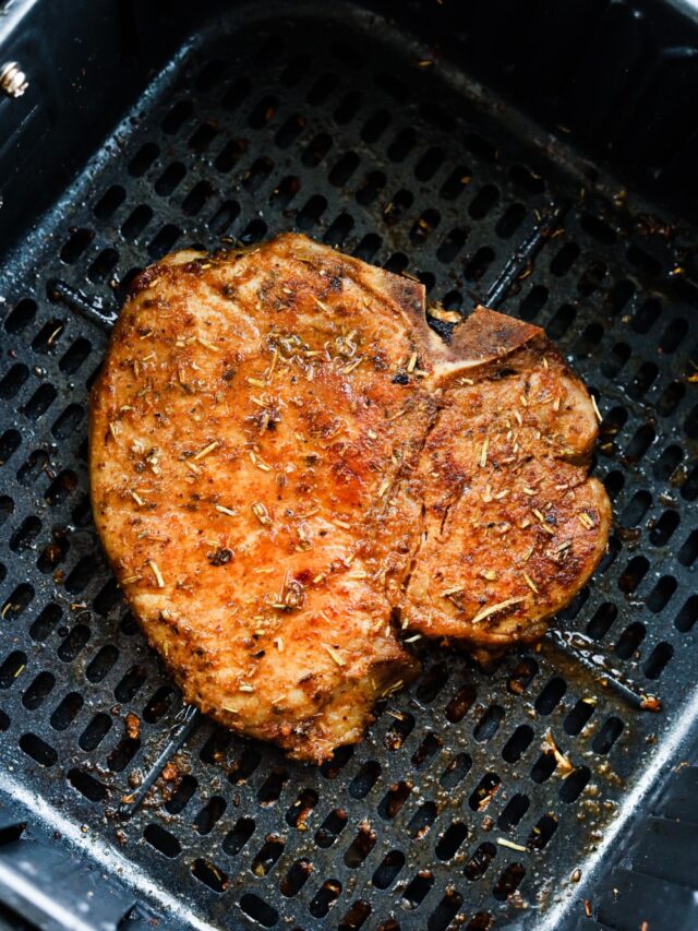 A cooked pork chop in an air fryer basket.