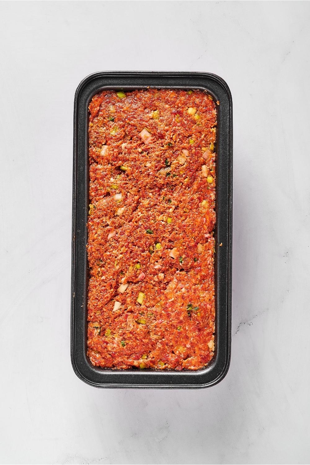 Meatloaf mixture in a loaf pan on top of a white counter.
