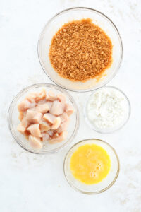 A variety of ingredients in glass bowls on a white table.