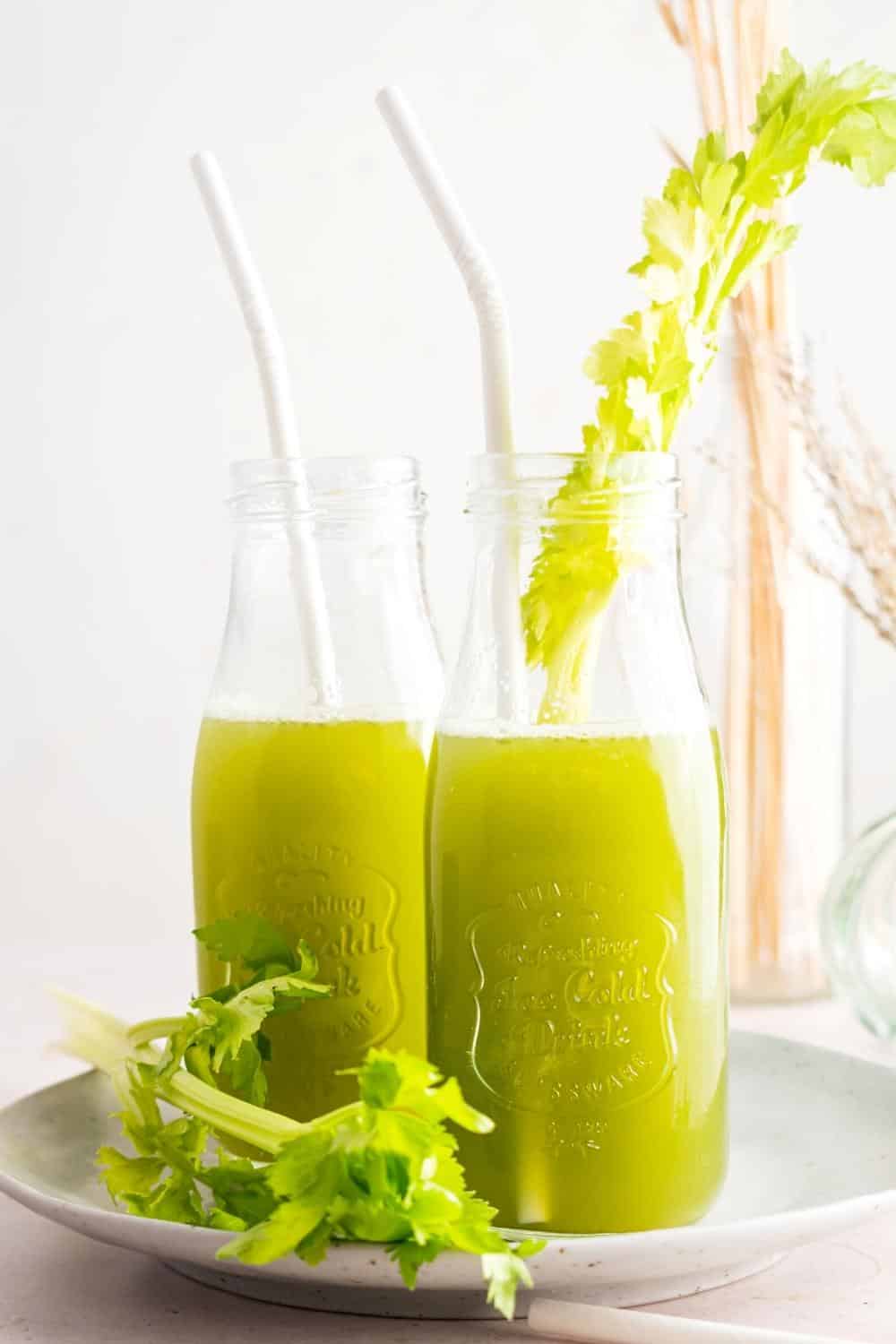 Two glasses with straws in them filled ¾ of the way with celery juice.