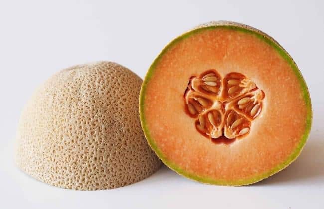 Half of a cantaloupe next to another half of a cantaloupe that is facedown.