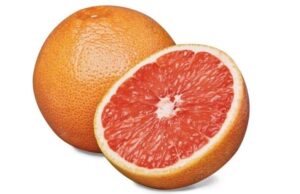 Half of a grapefruit in front of the whole grapefruit.