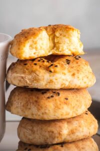 A stack of four bagels. The top bagel is cut in half.