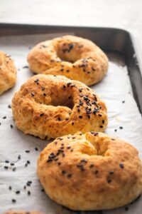 A row of three low-calorie bagels on part of a baking tray lined with parchment paper.