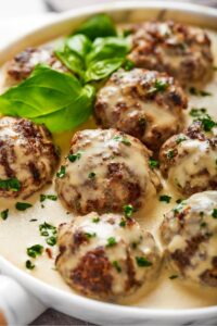 A few meatballs smothered in white gravy and a place that has the gravy on it.